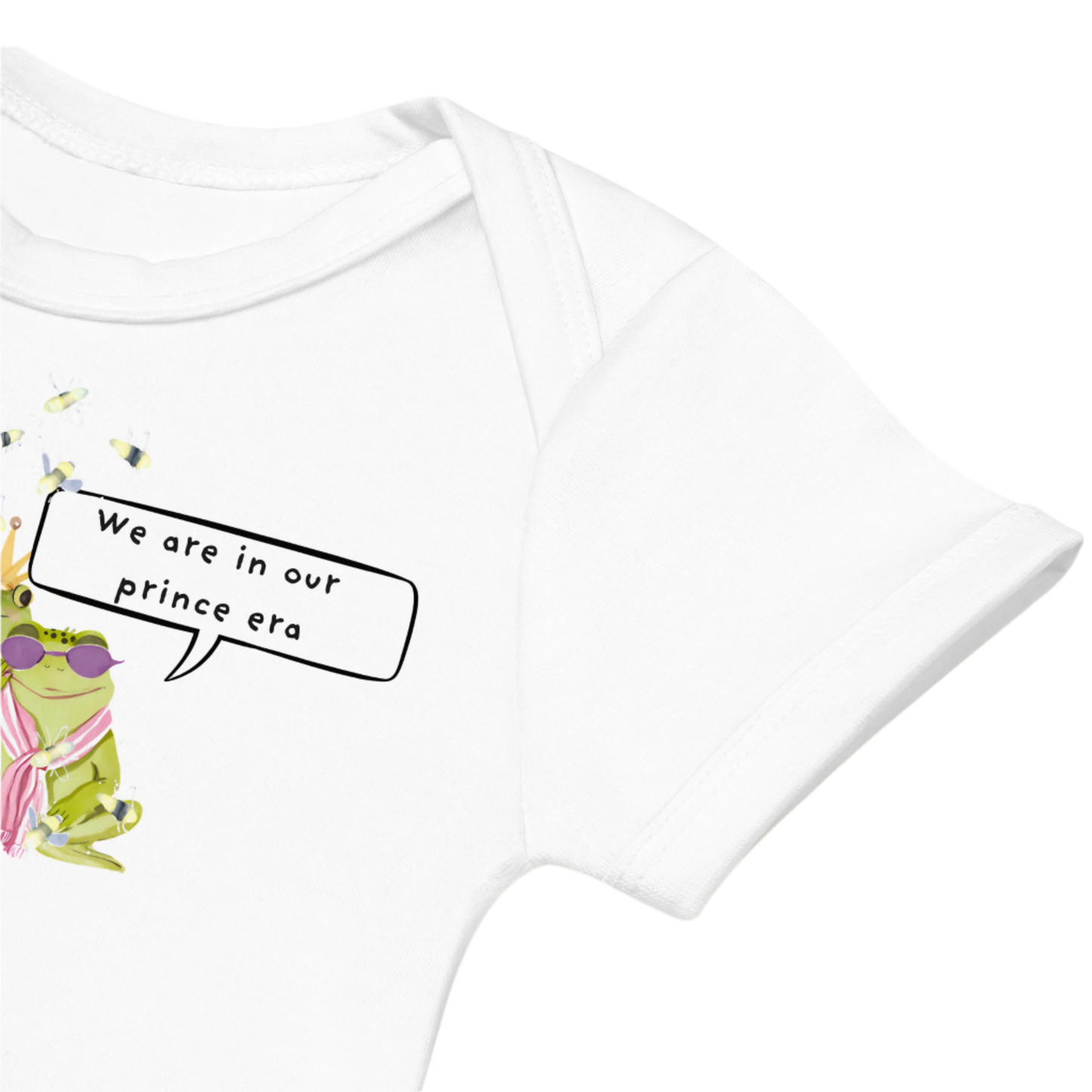 Up-close image of the white baby bodysuit with a funny frog-themed design
