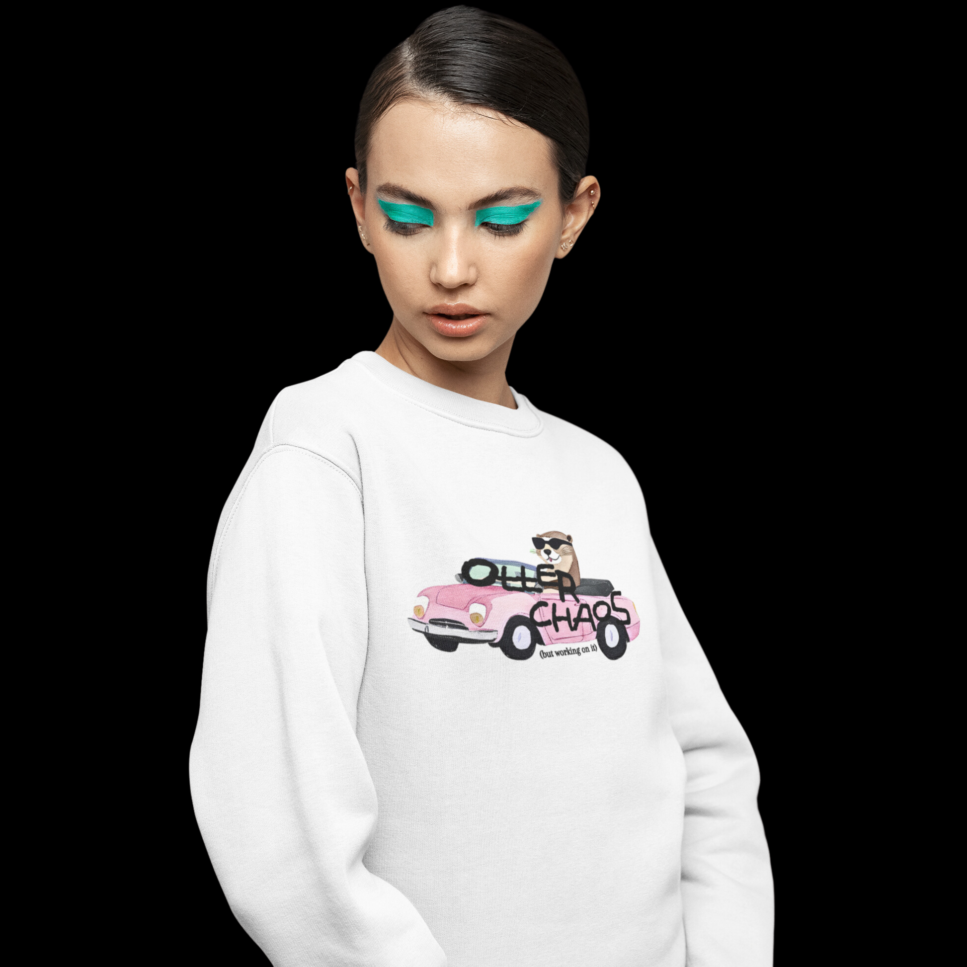 White crewneck sweatshirt with a graphic on the front of an otter driving in a pink car with the words "Otter Chaos" written on the front.